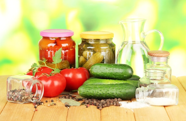 Concombres verts savoureux et tomates rouges dans un panier sur une table en bois sur fond clair