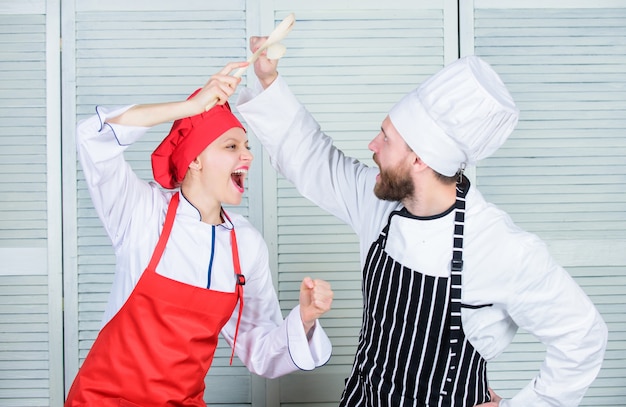 Concurrents du spectacle culinaire femme et homme barbu. Défi culinaire ultime. Bataille culinaire de deux chefs. Un couple s'affronte dans les arts culinaires. Règles de cuisine. Qui cuisine mieux. Concept de bataille culinaire.