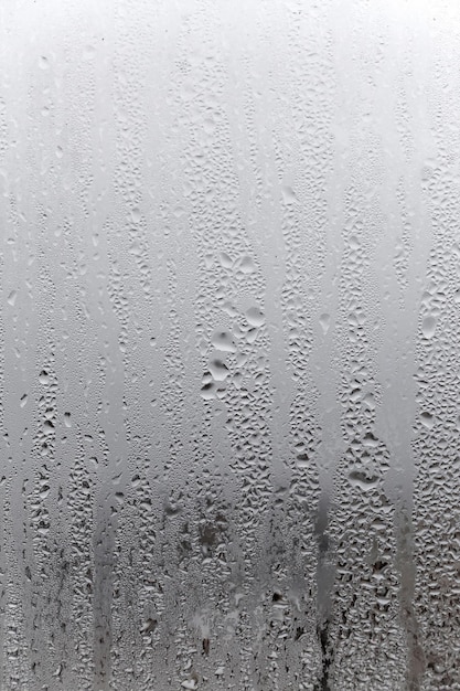 Condensation d'eau sur fond de verre de fenêtre En dehors de l'humidité de la pluie par mauvais temps et du brouillard blanc Fond naturel vertical