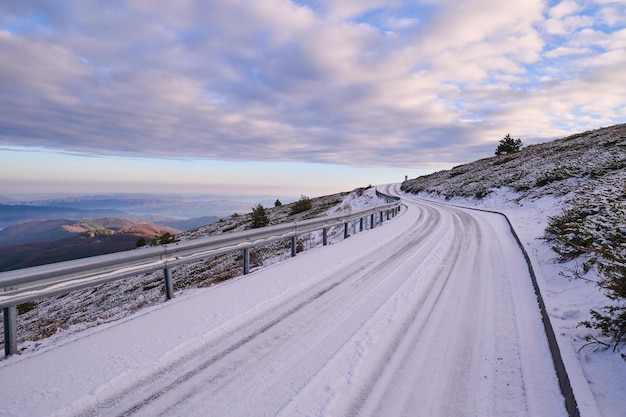 Conditions difficiles sur route enneigée dans les montagnes au lever du soleil