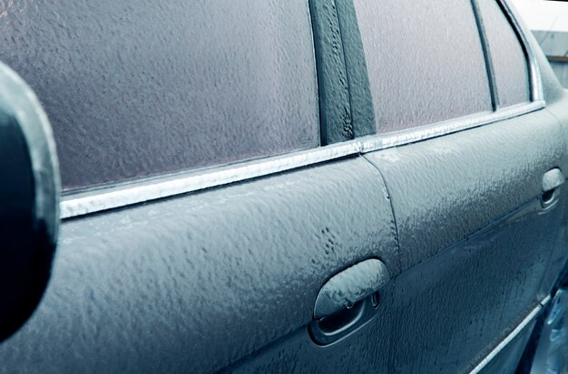 Conditions météorologiques difficiles en hiver, concept de mauvais temps, glace sur les routes, avertissement de tempête et niveau de danger orange. Mise au point sélective de voiture glacée et virage bleu.