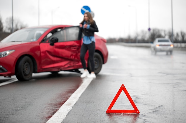 Photo conducteur assis au bord de la route après un accident de la circulation. l'accent est mis sur le signe triangle rouge