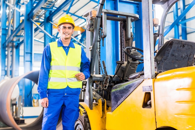 Photo conducteur de chariot élévateur debout fier dans l'usine de fabrication