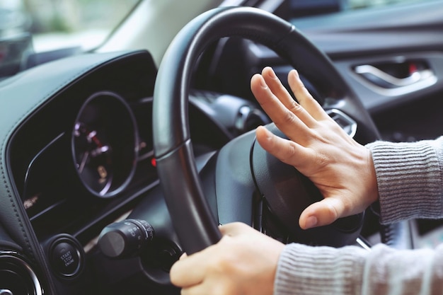 Un conducteur en colère klaxonne et crie en s'asseyant dans un embouteillage de roue de direction