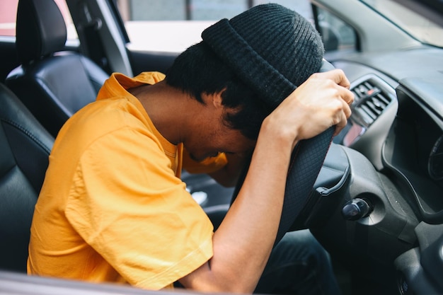 Conducteur fatigué, posant sa tête sur le volant de sa voiture pendant les embouteillages