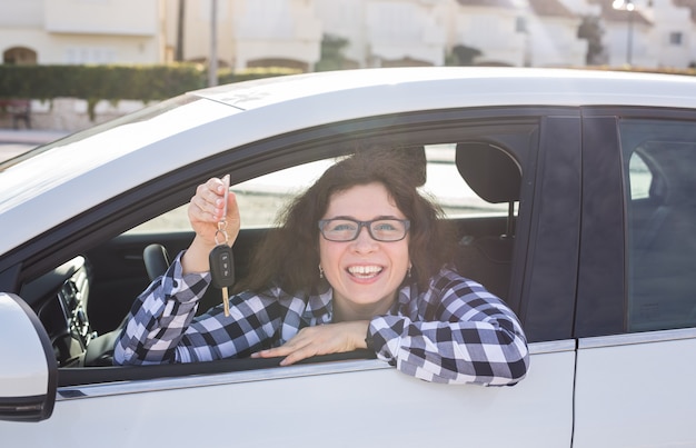 Conducteur de femme tenant des clés de voiture dans sa nouvelle voiture.