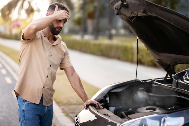 Conducteur inquiet tenant sa tête ayant un problème de moteur debout près d'une voiture cassée. Panne de voiture