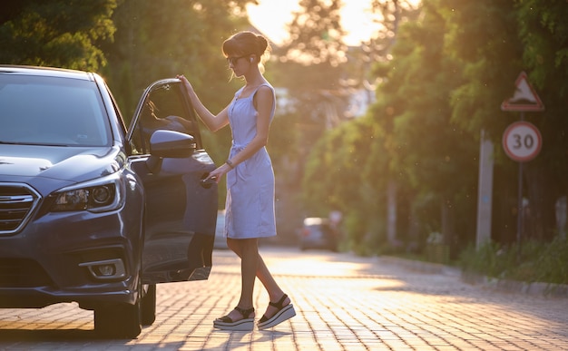 Conducteur de jeune femme entrant dans sa voiture. Concept de transport et de trafic.