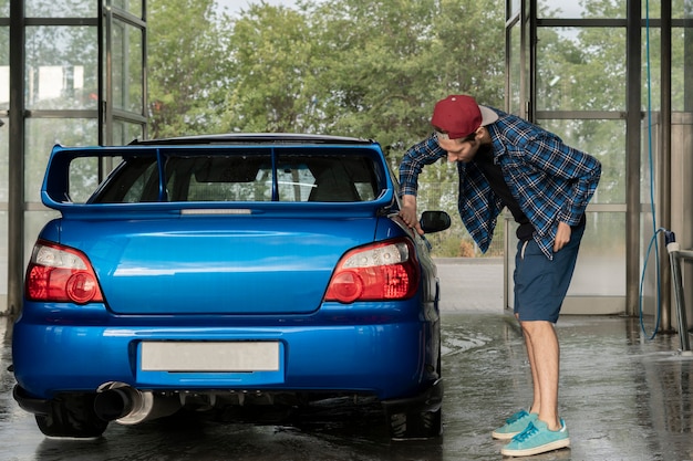 Un Conducteur De Sexe Masculin Nettoyant La Voiture à L'intérieur De La Boîte De La Station De Lavage Automatique