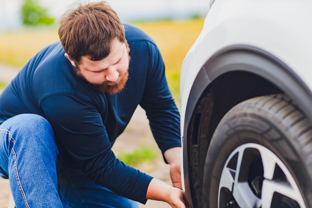 Conducteur stressé et frustré tirant ses cheveux tout en se tenant sur la route à côté d'une voiture cassée. Problèmes de road trip et concepts d'assistance. fumée.