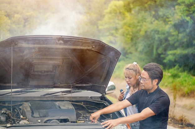 Un conducteur vérifie l'état d'une voiture après un accident avec un moteur qui fume