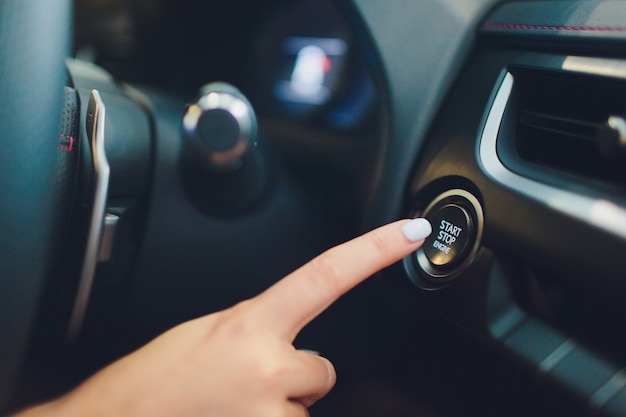 Photo conducteur de voiture démarrant le moteur sans clé. noir. main féminine.