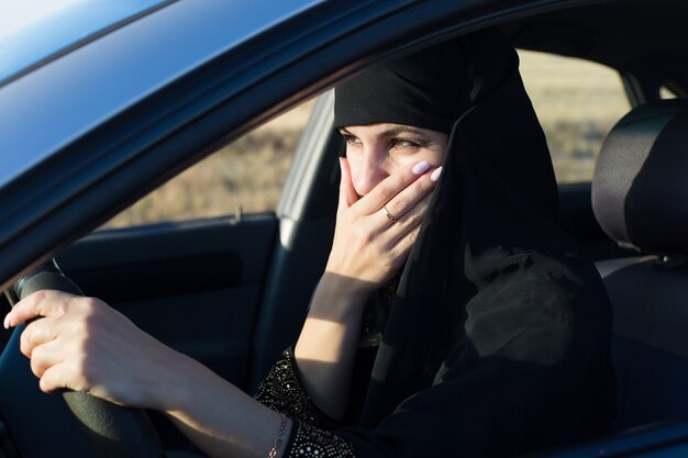 Une conductrice effrayée en conduisant a couvert sa bouche avec sa main.,