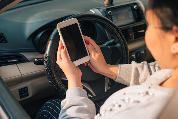 Conductrice utilisant un téléphone intelligent dans une voiture pendant les embouteillages, écran vide à des fins de conception.