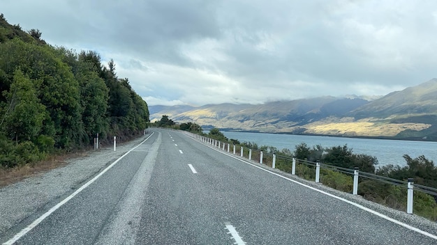 Photo conduire l'autoroute le long des montagnes et la rive du lac wakatipu entre queenstown et gl