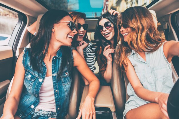 Conduire ensemble. Quatre belles jeunes femmes gaies se regardant avec le sourire