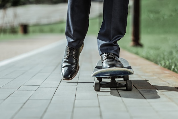 Conduite en douceur. Gros plan des pieds mâles debout sur une vieille planche à roulettes en roulant pour travailler