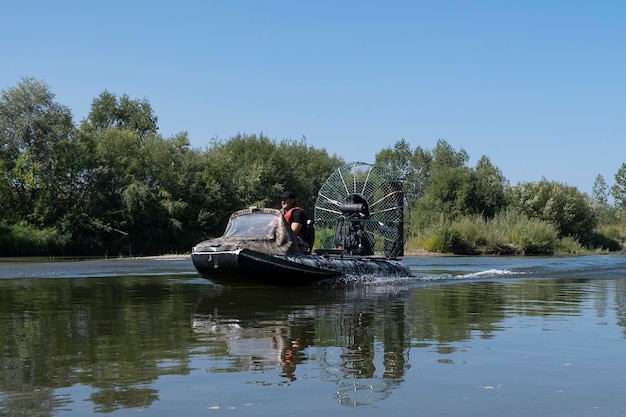 Conduite à grande vitesse dans un hydroglisseur sur la rivière un jour d'été avec des éclaboussures et des vagues