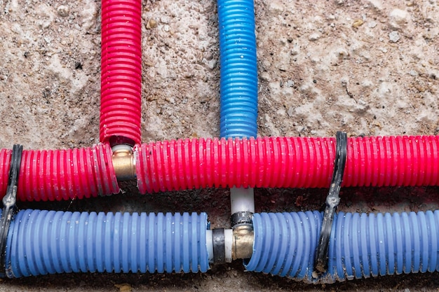 Conduites d'eau ondulées en rouge et bleu Système de plomberie dans le sol Tuyau posé sur le sol de la maison