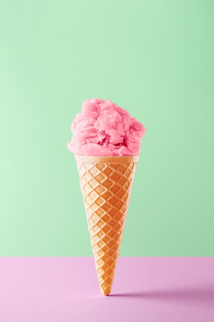 Un cône de crème glacée rose sur un fond vert