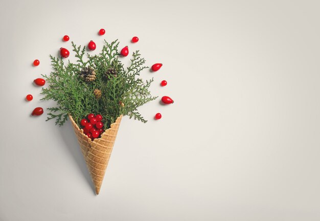 Cône de gaufre avec composition de branches de conifères, de baies et de strobiles