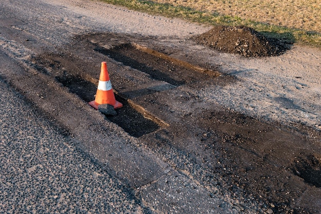 Cône orange blanc de danger de circulation sur la réparation de route d'asphalte