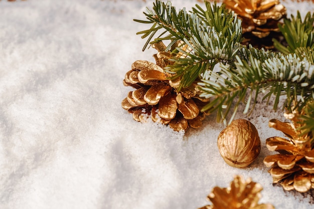 Cône de pin peint en or sur table enneigée, décor de Noël
