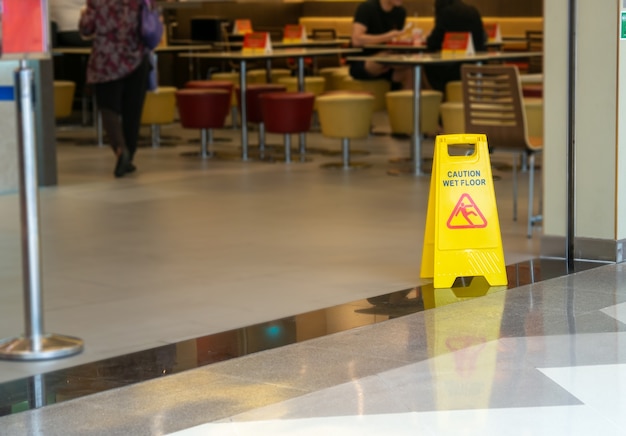 Cône en plastique jaune avec signe indiquant l&#39;avertissement de sol mouillé dans le restaurant dans le grand magasin