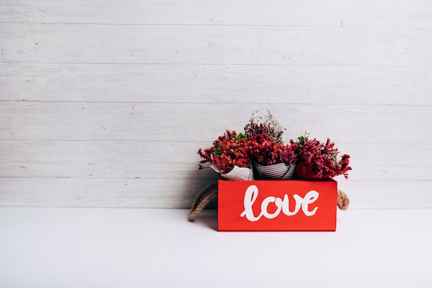 Cônes de fleurs dans la boîte d&#39;amour sur un bureau blanc sur fond de bois