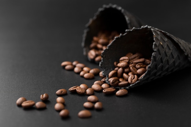 Cônes noirs avec des grains de café sur une table sombre