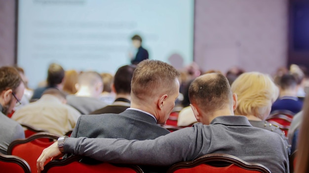 Une conférence d'affaires Des gens assis dans le hall et regardant la présentation Deux hommes qui parlent