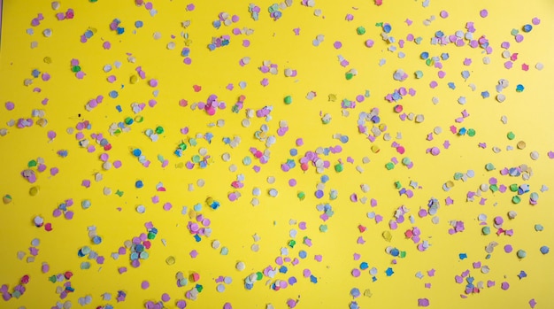 Confettis de carnaval ou de fête d'anniversaire sur fond jaune vif