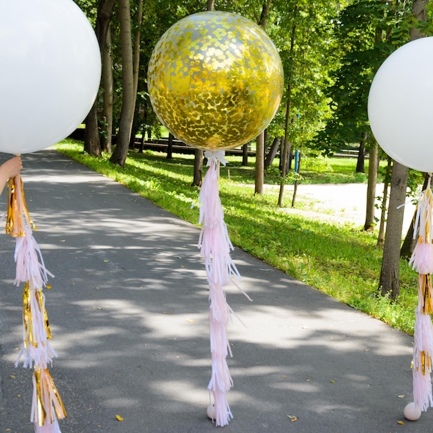 Photo confettis d'or géants et ballons blancs