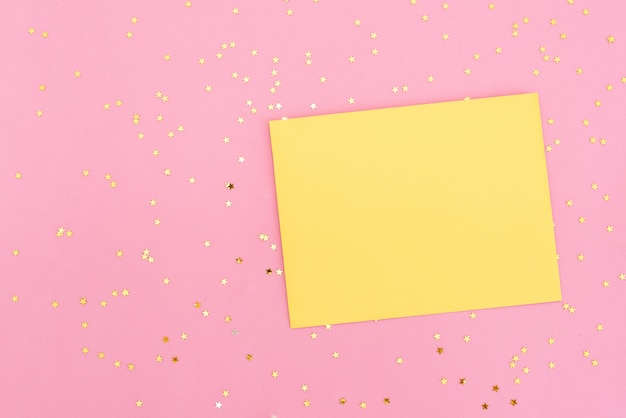 Confettis or et rose coulant de l&#39;enveloppe blanche sur fond rose pastel.