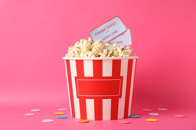 Confettis, seau avec pop-corn et billets sur fond rose