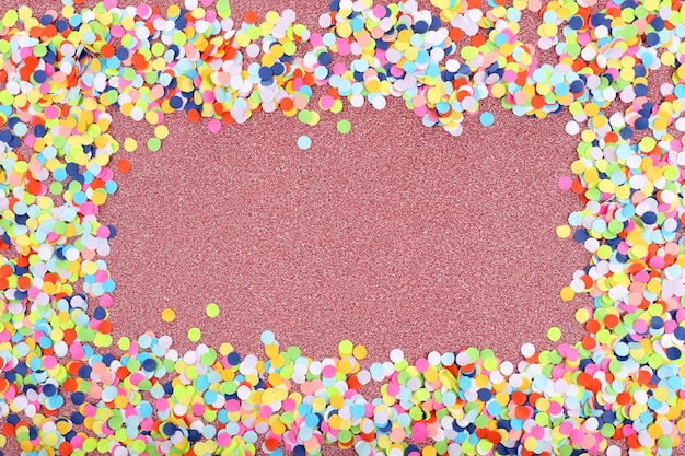 Confettis sur une surface rose brillante