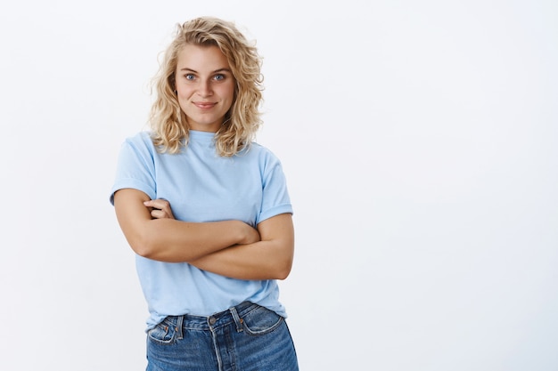 La confiance est la clé du succès. Portrait d'une jeune femme des années 20, enthousiaste et séduisante, sûre d'elle, aux cheveux blonds et aux yeux bleus, tenant les mains croisées dans une pose affirmée et ambitieuse, souriante