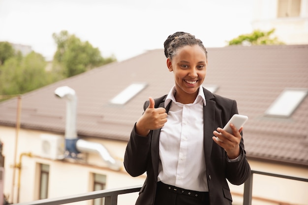 Confiance. Femme d'affaires afro-américaine en tenue de bureau souriante, a l'air confiante et heureuse, occupée. Concept de finance, d'entreprise, d'égalité et de droits de l'homme. Belle jeune femme modèle, réussie.