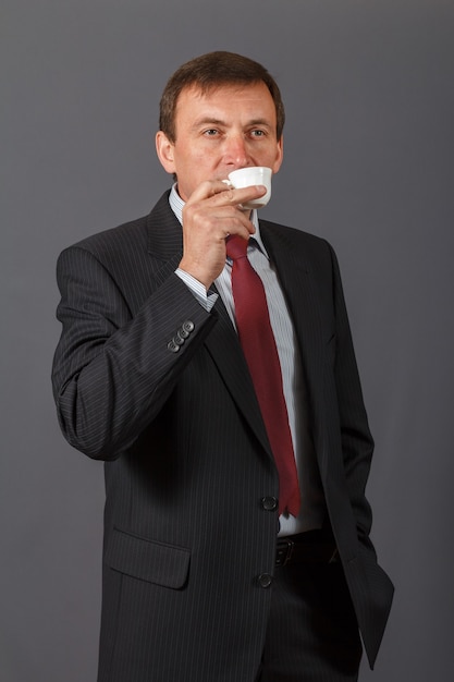 confiant et amical élégant bel homme d'affaires mature prenant une tasse de café