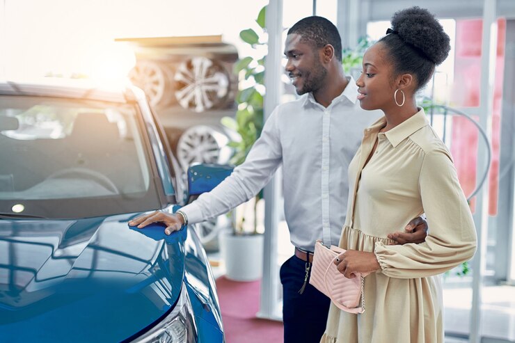 Photo confiant bel homme afro montre à sa femme une voiture qui lui plaît, ils regardent la voiture et discutent