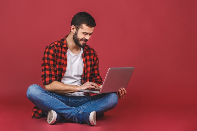 Confiant bel homme dans des vêtements décontractés travaillant sur ordinateur portable