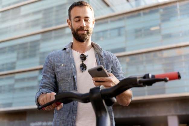 Confiant bel homme latin utilisant une application mobile scannant le code qr pour la location de scooter électrique