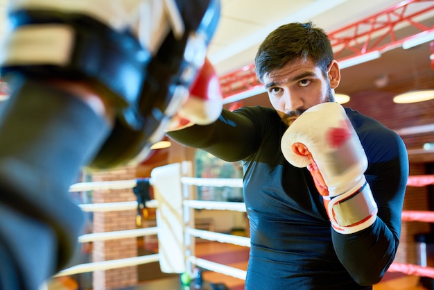 Confiant boxer punching pads on ring