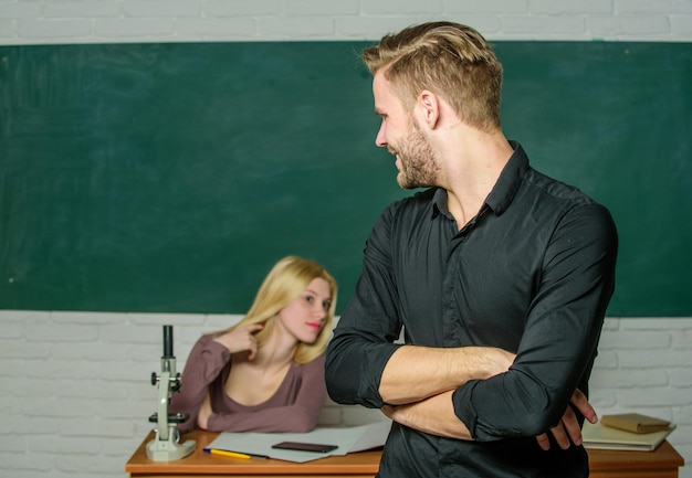 Confiant dans ses connaissances Bel homme debout les mains croisées dans la salle de classe avec l'enseignant Étudiant masculin avec examinateur à l'examen Lycéen disant la leçon Étudiant universitaire ou collégial