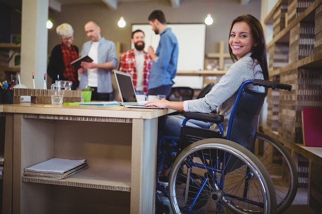 Confiant femme d'affaires handicapée utilisant un ordinateur portable au bureau