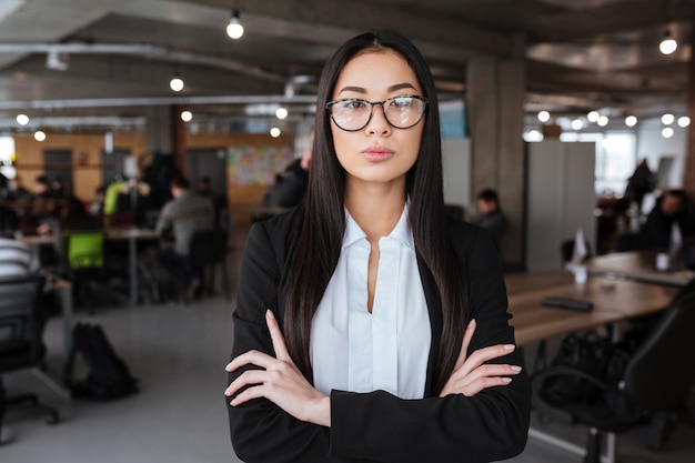 Confiant jeune femme d'affaires asiatique debout avec les bras croisés au bureau