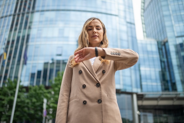 Confiant jeune femme manager vérifier l'heure sur sa montre en plein air