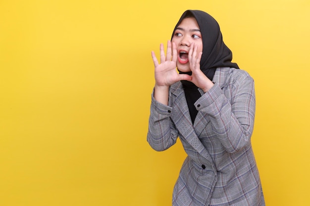Confiant jeune femme musulmane debout avec les mains à côté de la bouche à la recherche de copier l'espace dans l'excitation un