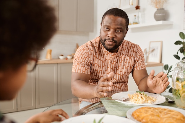 Confiant jeune homme africain parlant à son petit fils par dîner