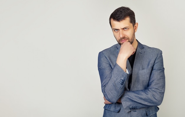 Confiant jeune homme avec une barbe tient sa main sur son menton